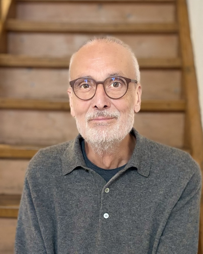 Portrait von Paul Janouch vor einer Holztreppe.